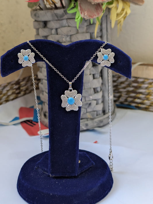 Flower-shaped necklace with blue stones on a blue velvet stand.